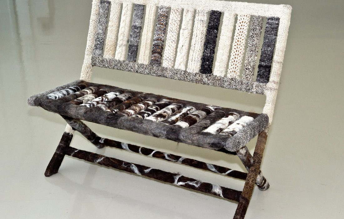 Knitting Salon_Bench_Cred Trevor Pitt (1) A bench covered in patterned woollen pieces of various cream, grey and brown colours.