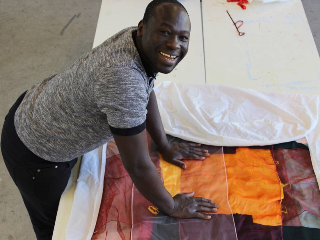 Andrew smiling whilst in the studio working on one of his textile pieces