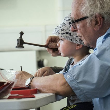 metal2 An older man works with a young boy hammering a metal punch.