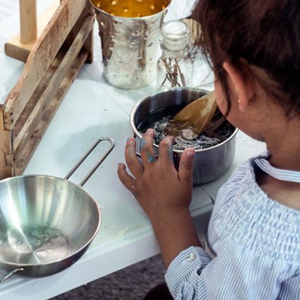 metal5 A toddler stirs objects in a saucepan.