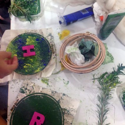 3 A table covered with embroidery hoops, paint and leaves.