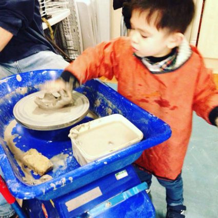4 A boy reaches to touch clay spinning on a potter's wheel.