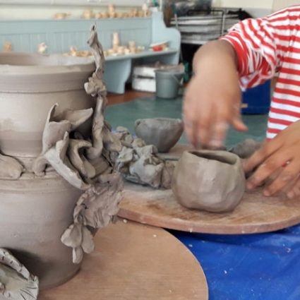 9 A very young child investigates a wet clay pot.