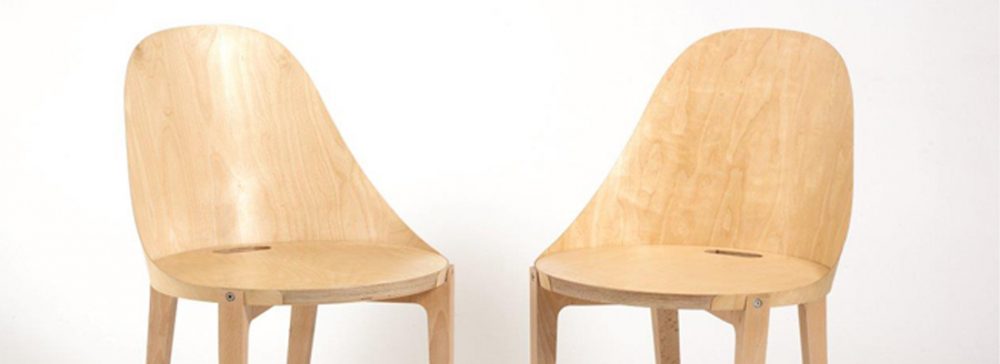 Two wooden dining chairs, simple in design with a round seat and full shaped back.