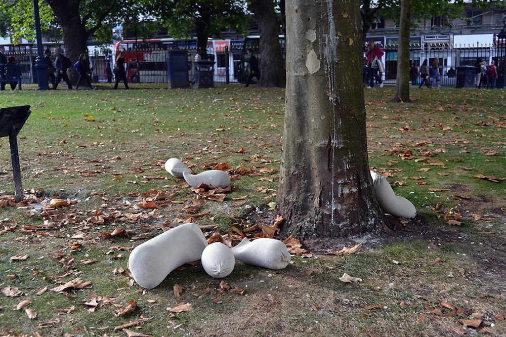 Six textile sculptures lie on the ground, made of cloth and wadding, one lies against a tree.