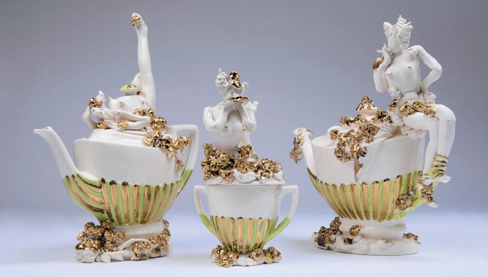 Three intricate and extravagent ceramic pots - two teapots and one lidded pot with gold roses and ladies.
