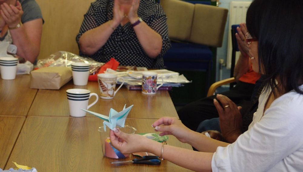 A member of Shelanu teaches participants how to make an origami bird.
