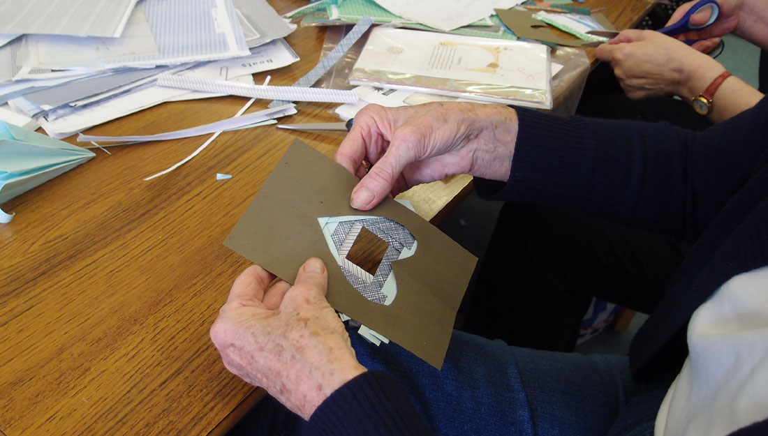 An older lady learns how to make a card from paper.