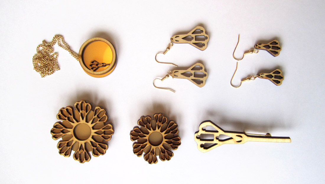 six pieces of jewellery laid out in two rows of three, made from acrylic in gold/yellow colour and laser cut wood.
