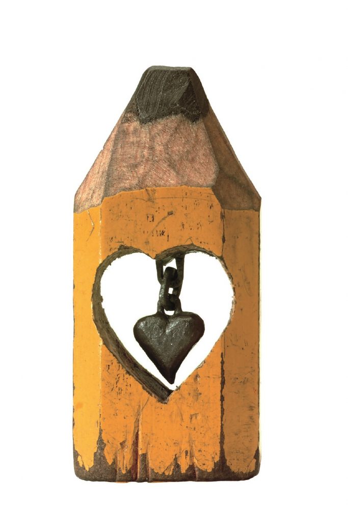 A tiny heart is carved from the lead of a pencil, the rest of the pencil is intact around it.