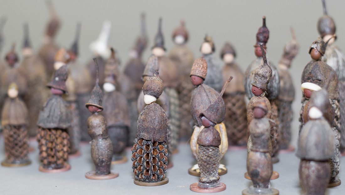 Lots of tiny figures standing in rows made from nuts and seeds.