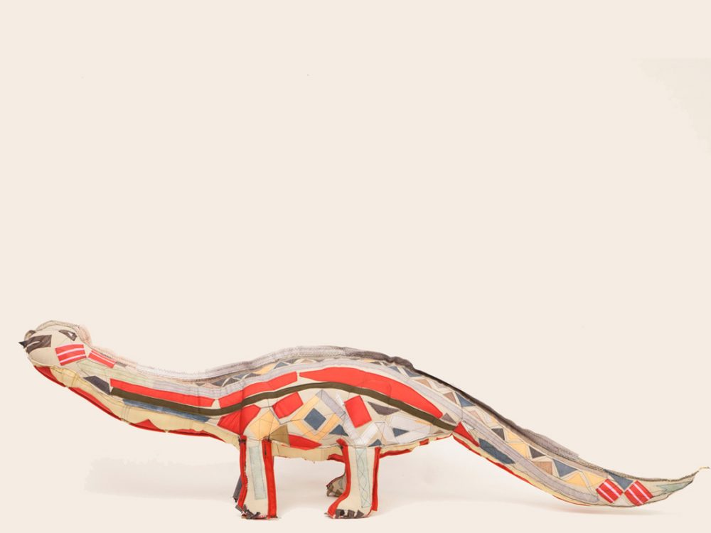 A 3D dinosaur made from textiles in a patchwork formation.