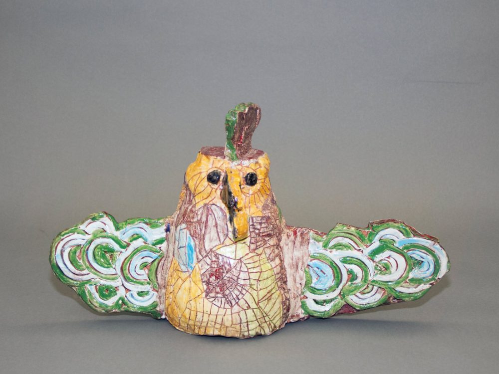 A ceramic bird with open wings decorated with different colours.