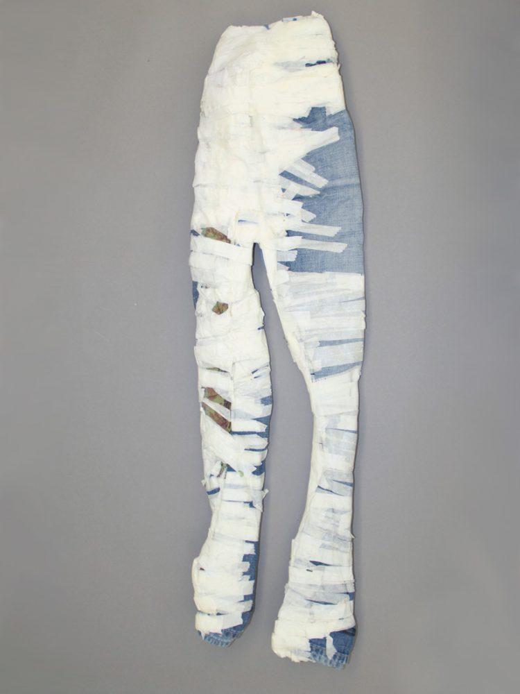 A pair of 3D jeans covered in tape sit on a wall.