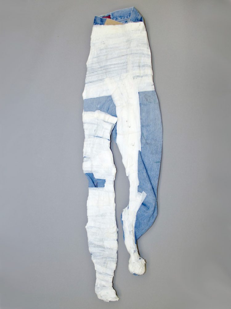 A pair of 3D jeans covered in tape sit on a wall.