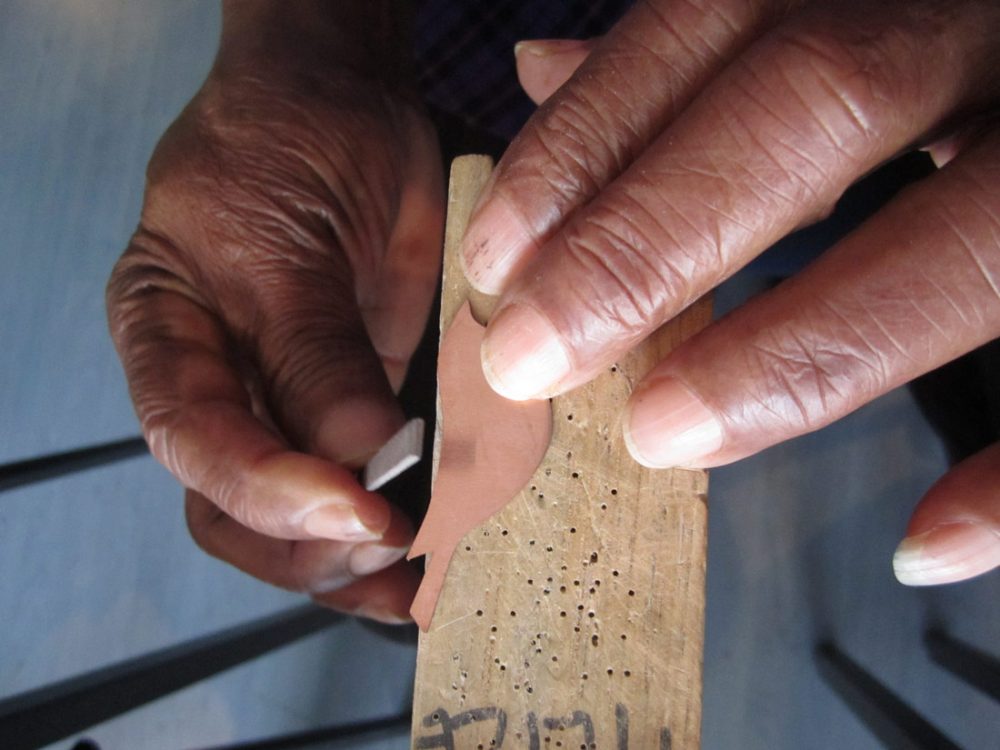 close up of Shelanu members hands filing one of the metal bird jewellery pieces