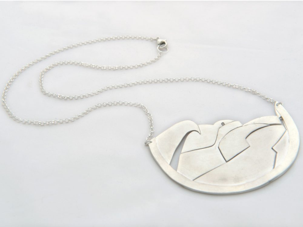 A silver necklace with simple abstract shapes that fit together made by Shelanu.