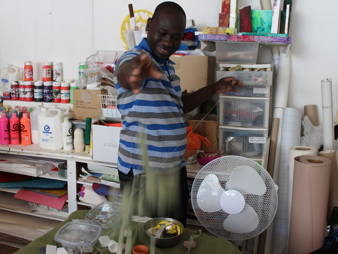 Andrew in the studio smiling and throwing fabric whilst holding a length of thread