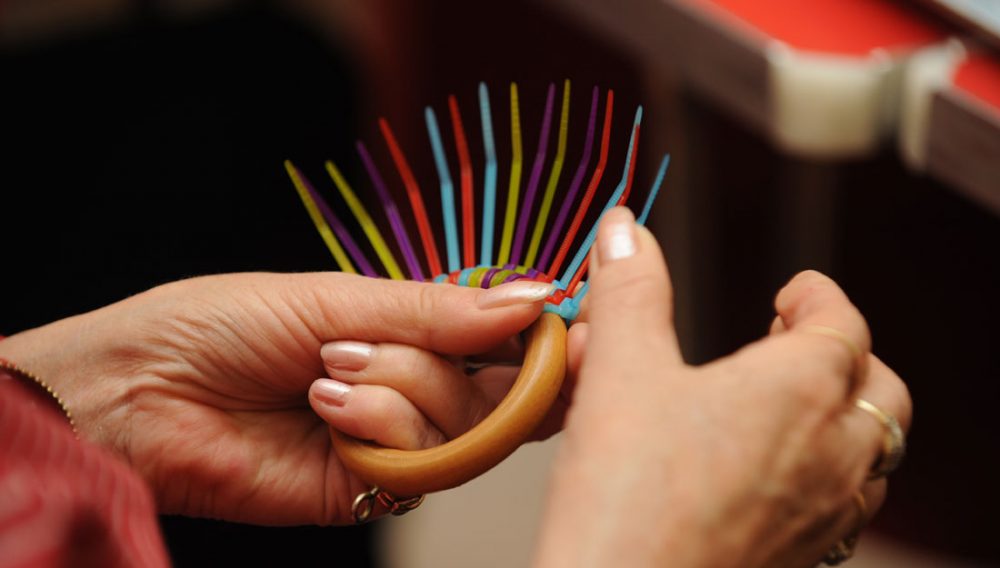 A lady adds coloured fastenings to a hoop.