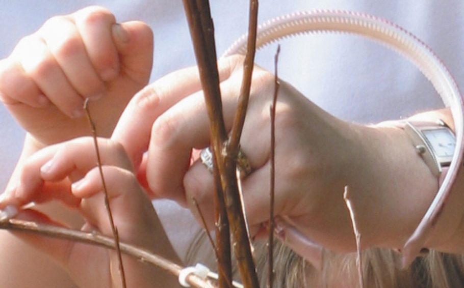 An adult and young child place objects onto branches.