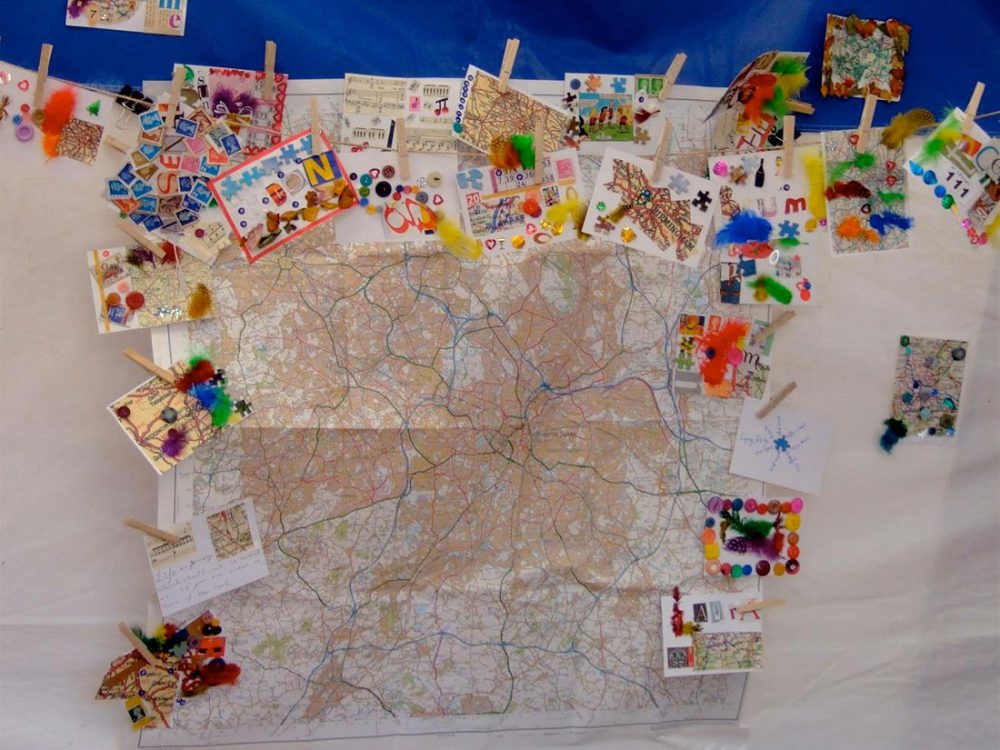 A large map of Birmingham placed on the wall is surrounded by small collages made by the public.