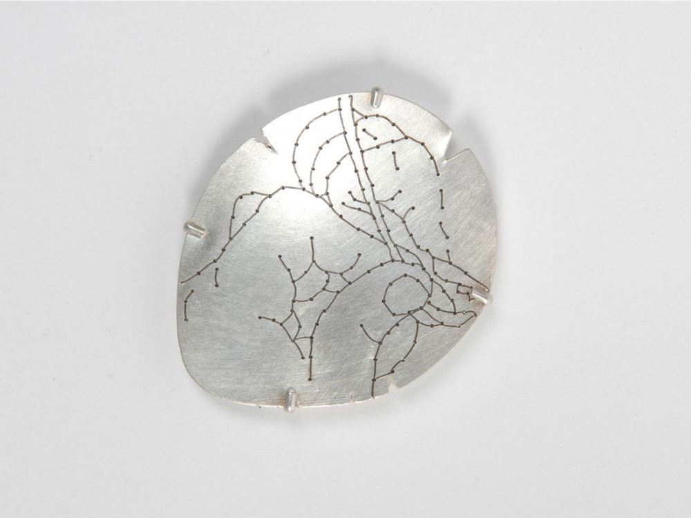 A flat piece of metal with holes that have thread through them showing an image of hands and thread.