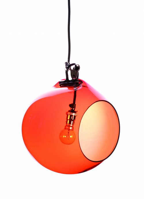 A orange sphere shapes light with a circle shaped hole cut out at the front hangs from the ceiling with a light bulb inside.