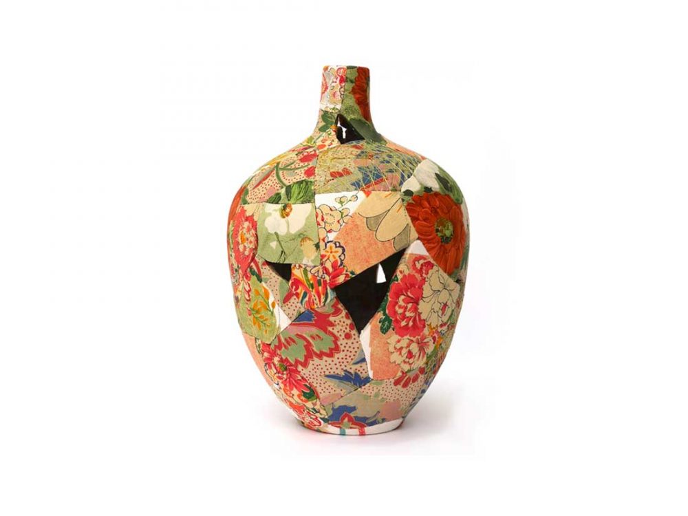 A vase is reformed from broken pieces covered in bright fabric and stiched back together.