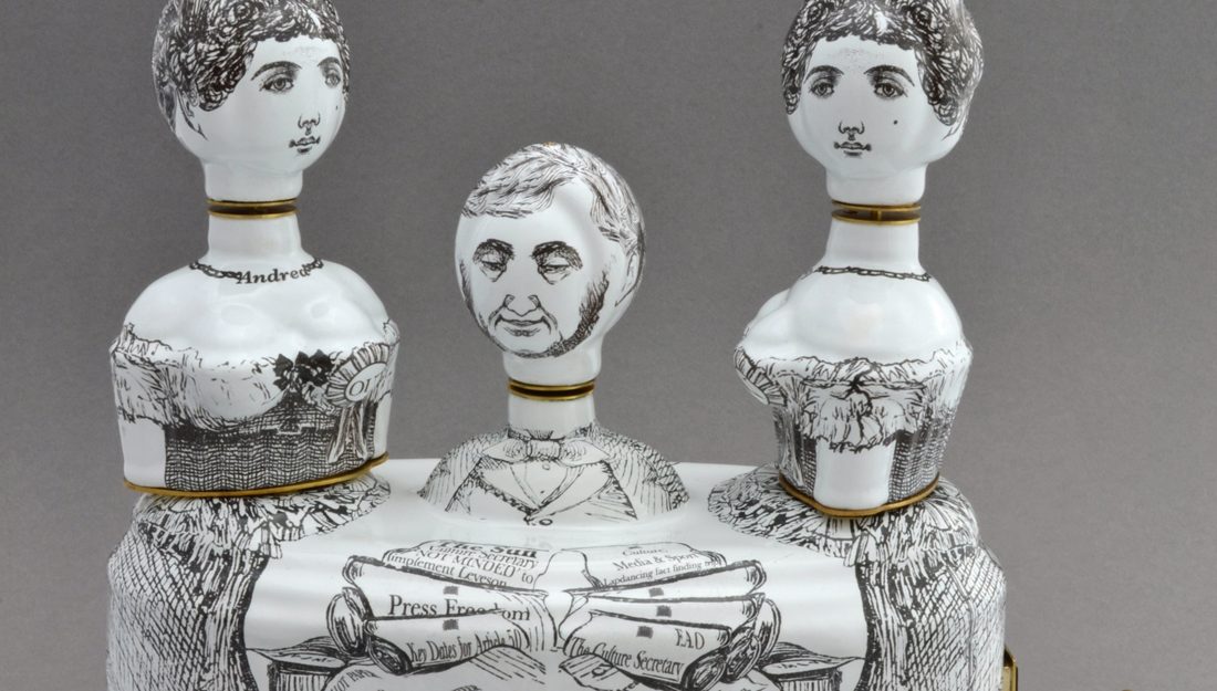 A satirical ceramic sculpture featuring 3 figures with black line drawing markings.