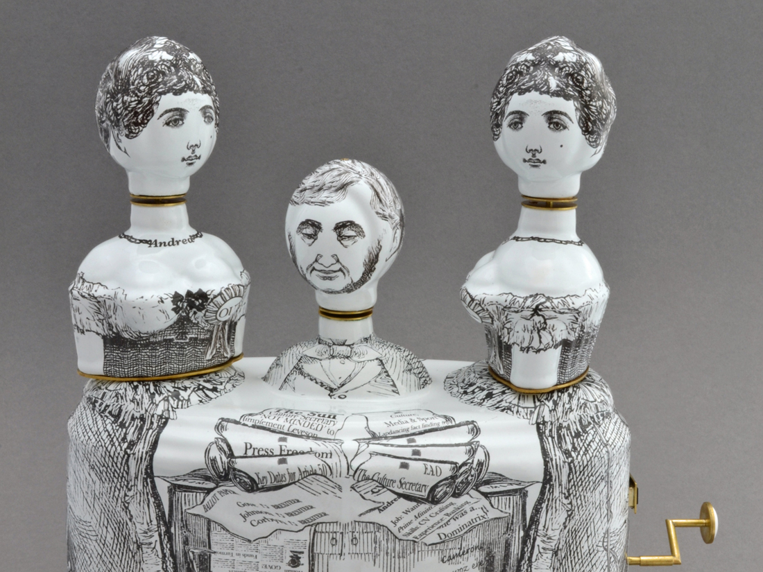 A satirical ceramic sculpture featuring 3 figures with black line drawing markings.