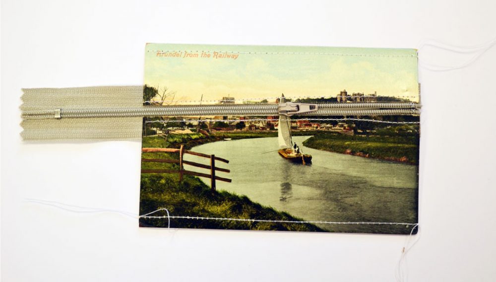 vintage postcard with image of Arundel featuring a grey zip going through the postcard revealing a second blank postcard underneath