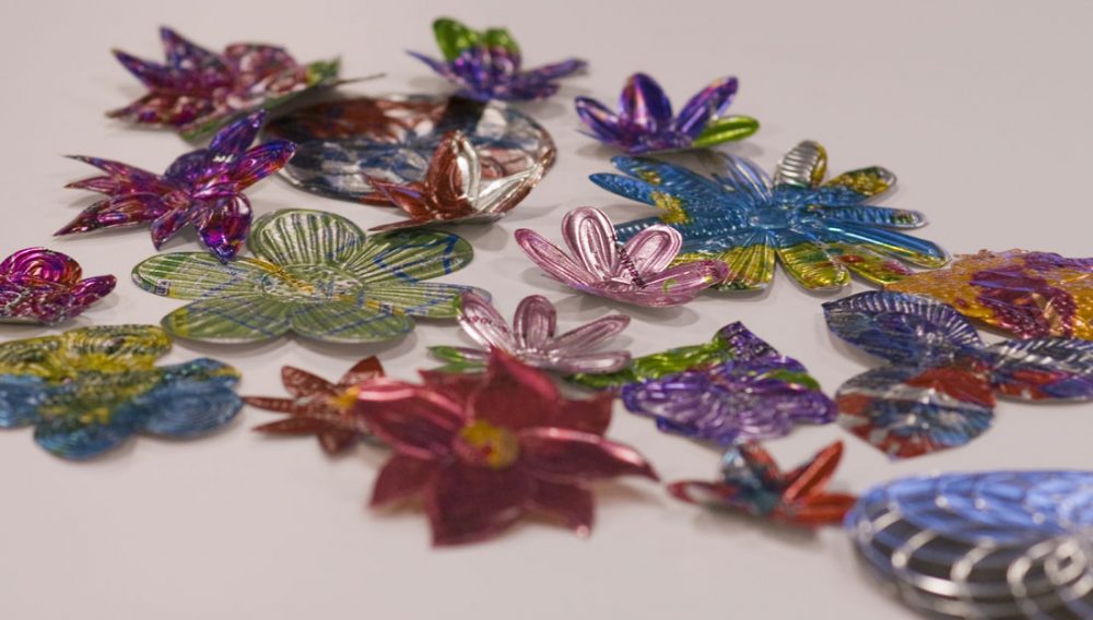 Various flowers made of sheet metal with different colours and textures applied to them.