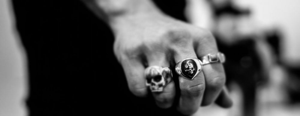 A hand wearing rings designed with skull motifs.