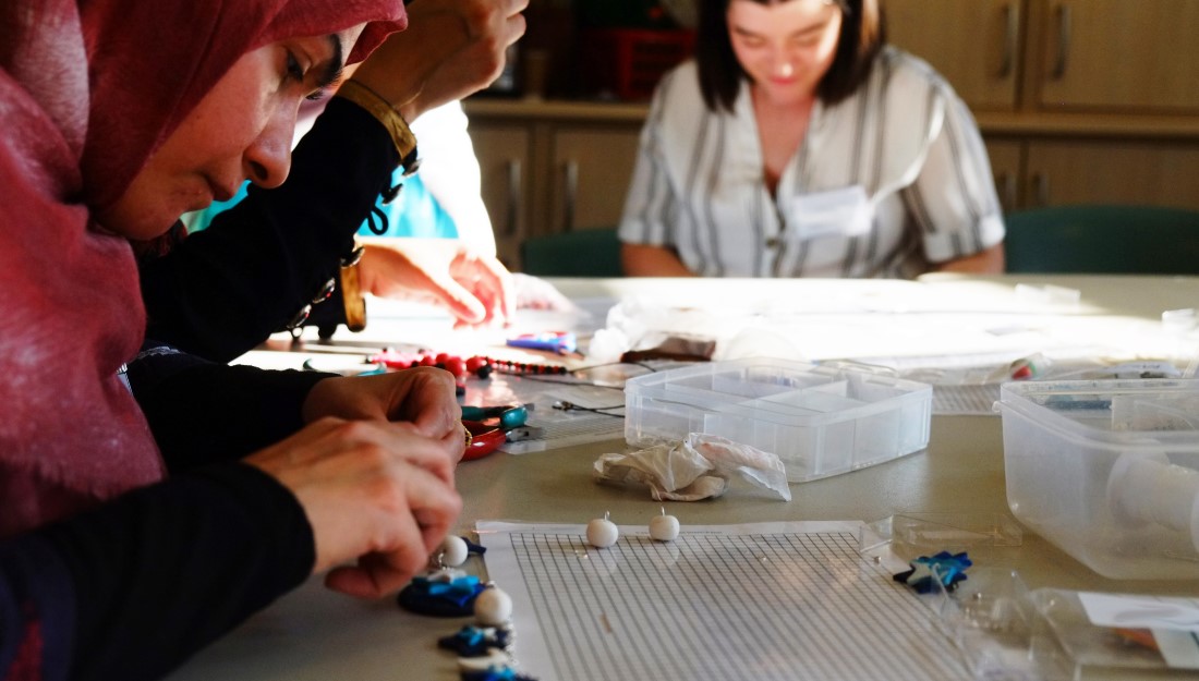 Women work on their jewellery in quiet concentration.