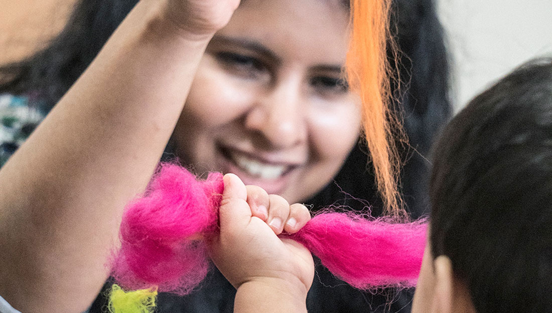 A woman interacts with a child using brightly coloured felts.