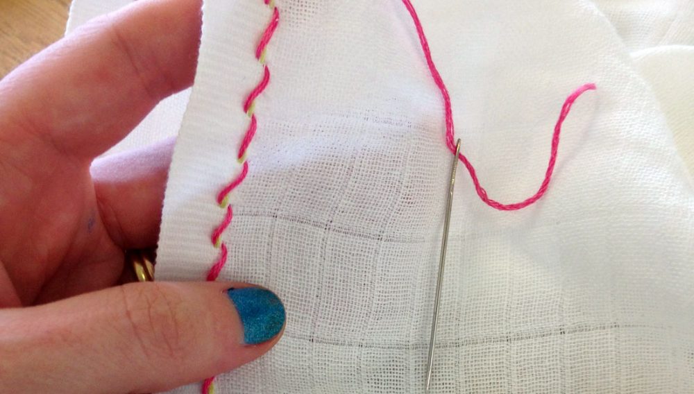 Stitching into white material using pink thread.