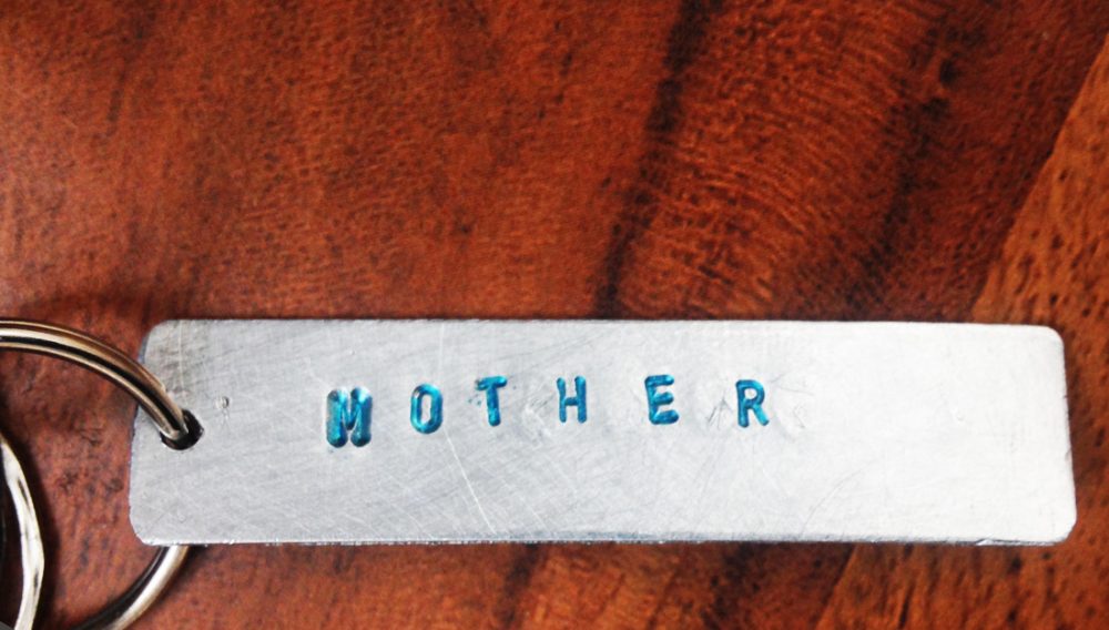Aluminium keyring with the word mother stamped into it in blue.