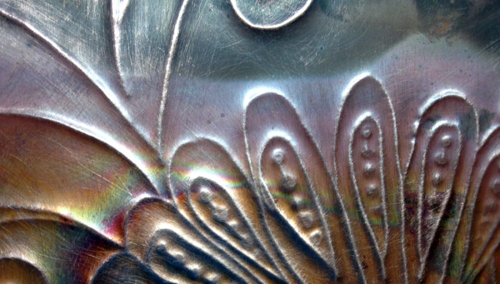 Close up of copper with flower design rolled into it.