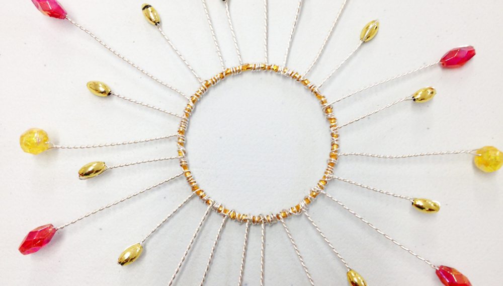 A sun shape made from jewels and wire.