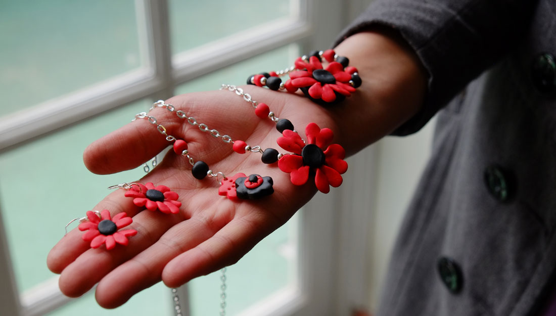 a hand held out with jewellery draped over.