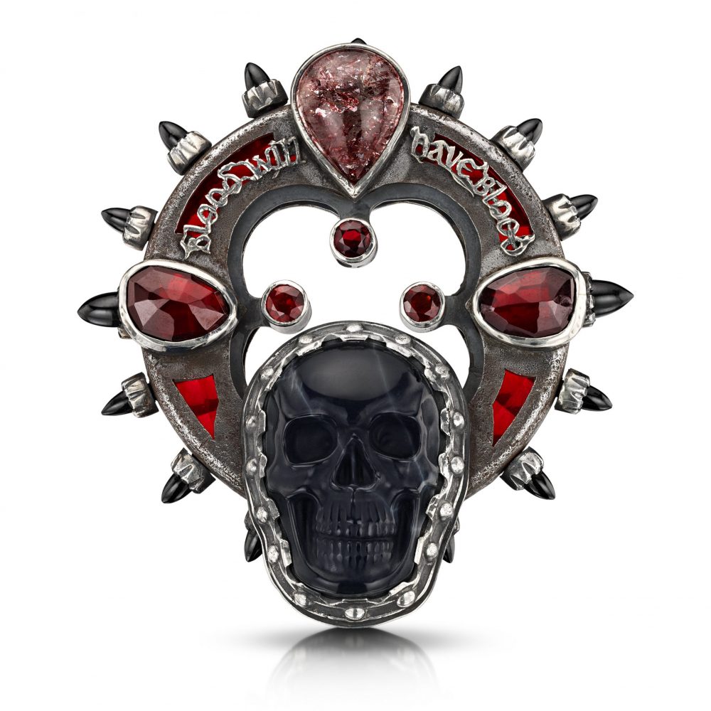 An elaborate brooch featuring a skull and a quote from Macbeth.