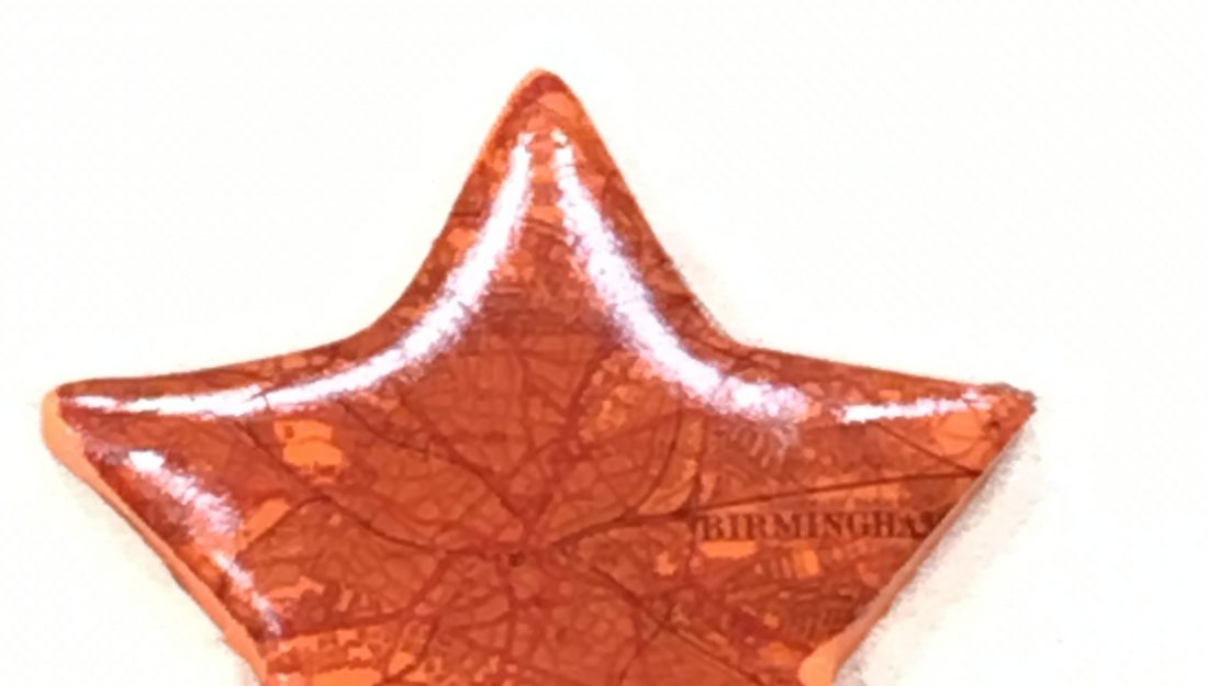 An transparent orange star pendant with a map background.