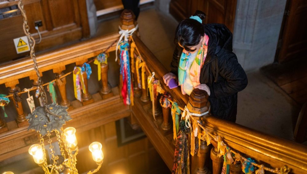 A delegate looks down the stairs at Gawthorpe Hall where there are strips of colourful fabric hanging from bannister