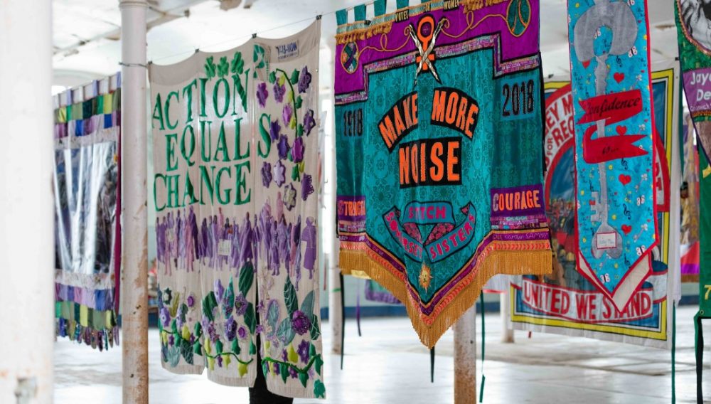 colourful banners hanging in space, reading 'Action Equals Change' and 'Make More Noise'
