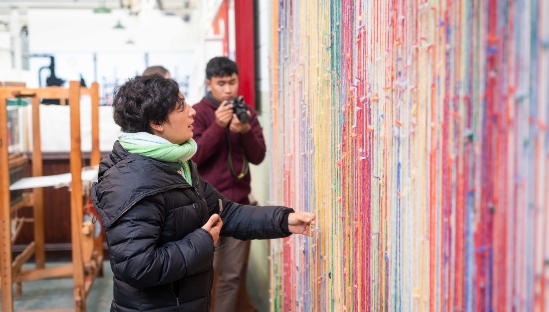 a delegate touches and admires colourful hanging threads installation on a wall