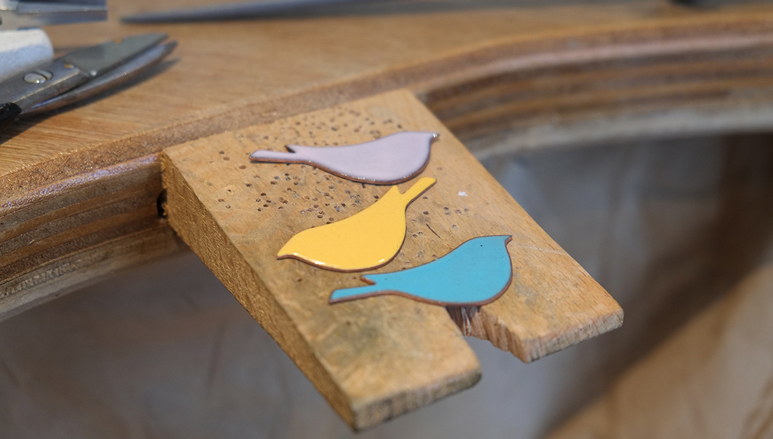 three enamelled birds on a jeweller's peg