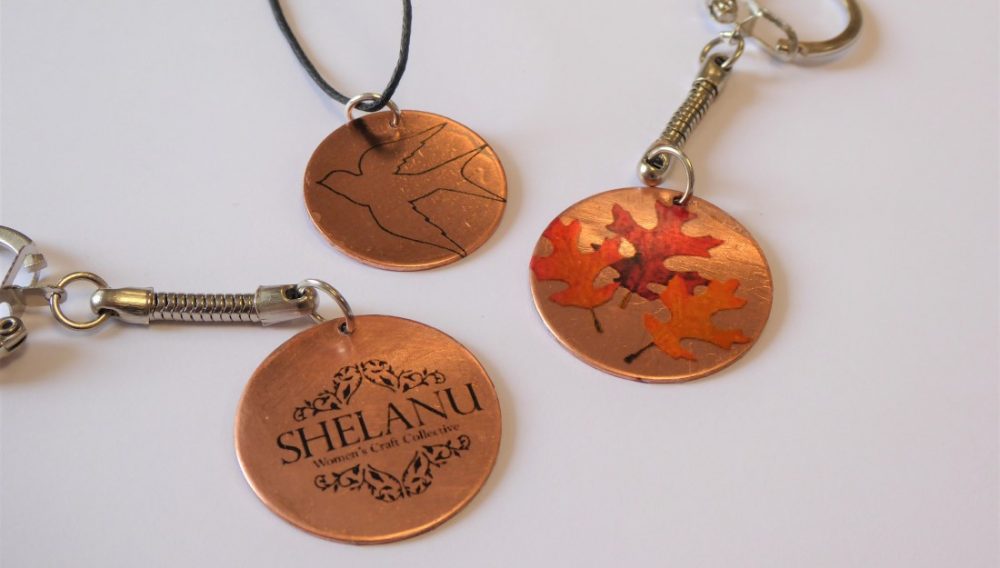 three copper discs, one with a bird, one with leaves and one that says Shelanu