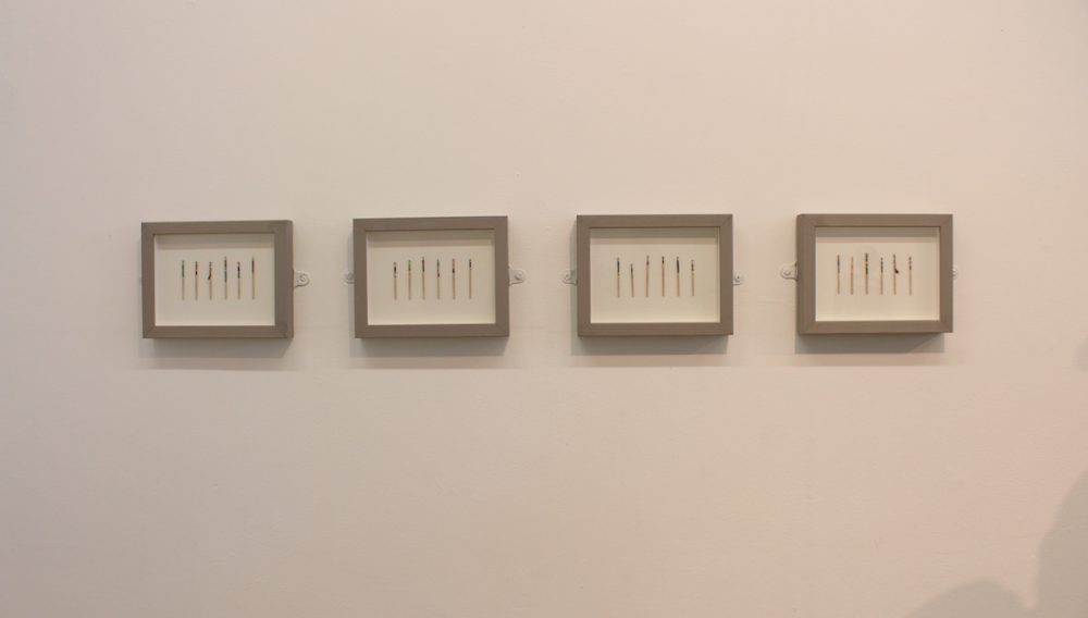 rows of painted toothpicks displayed in 4 frames on a wall
