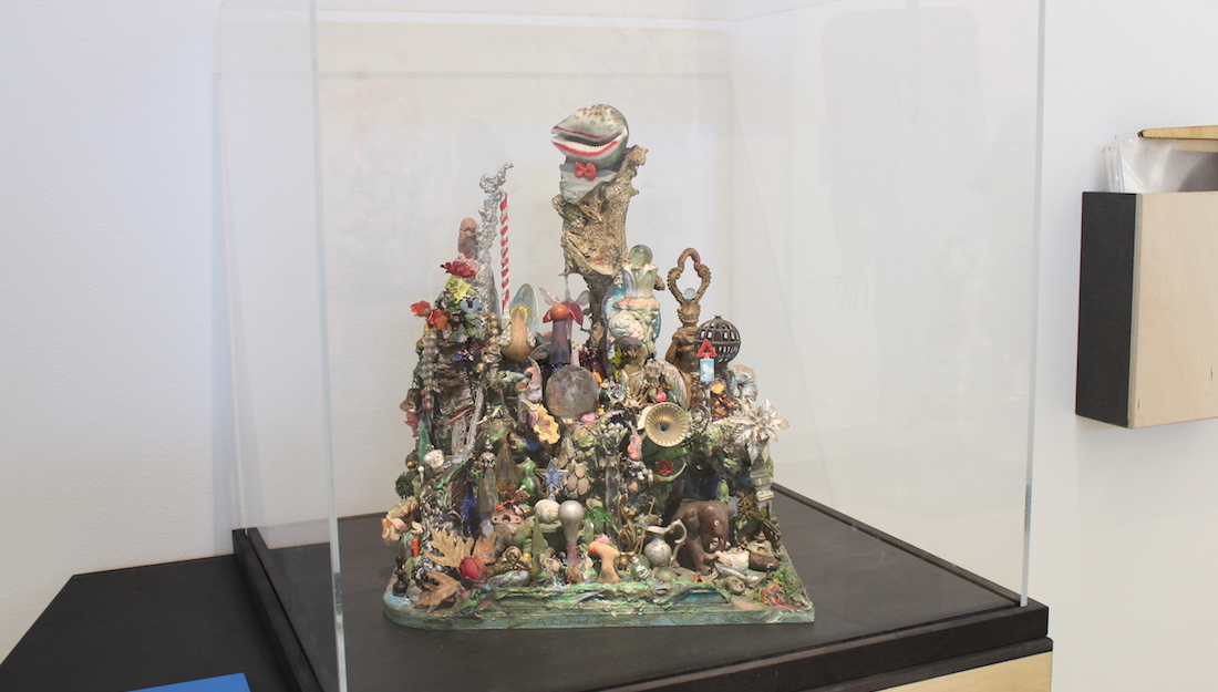 sculpture made from assembling various objects and trinkets in an exhibition case