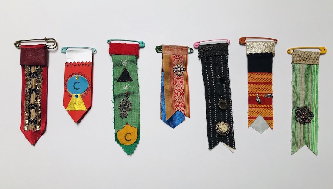 a row of 7 handmade fabric medals using various patterns and colours